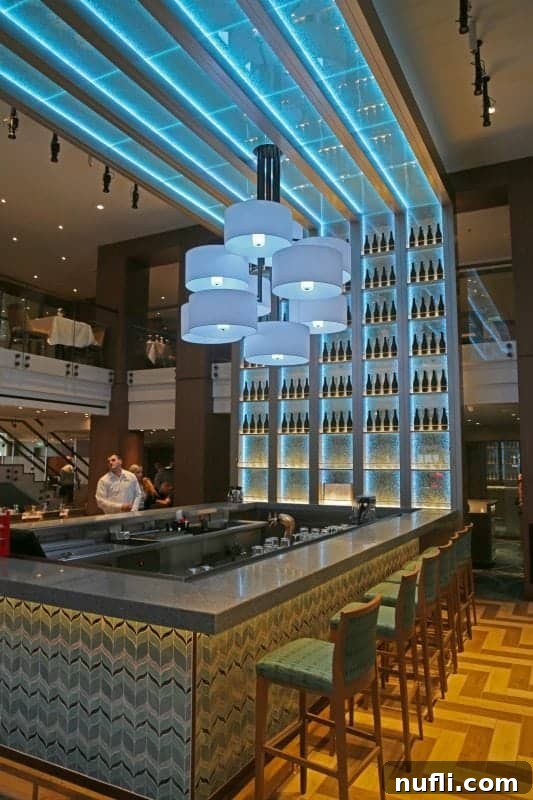 Bar area with tall chairs, blue lights and a fun chandelier in Reflections dining room 