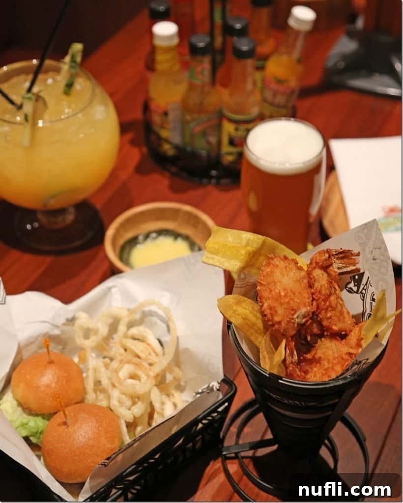 Table with coconut shrimp, sliders, fish bowl drink, and a glass of beer in Red Frog Brewery