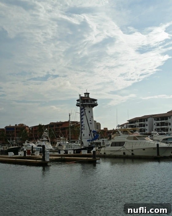 boats in a marina with a small lighthouse behind them in Puerto Vallarta