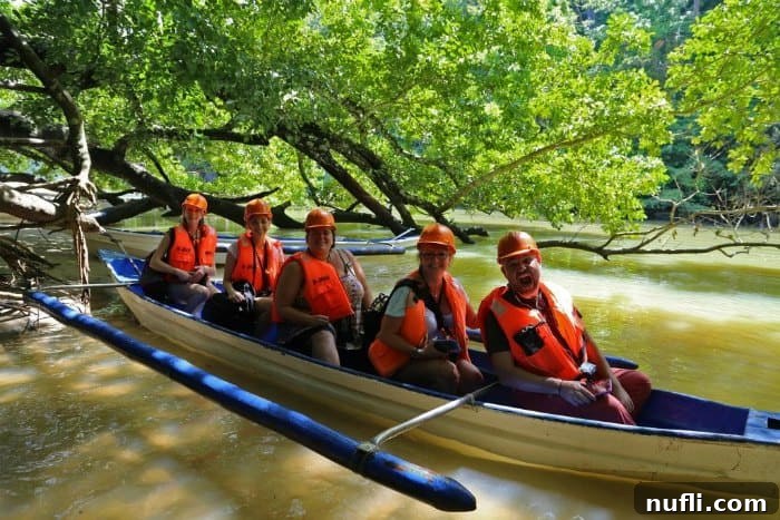 5 people in orange lifejackets and hardhats in a small canoe 