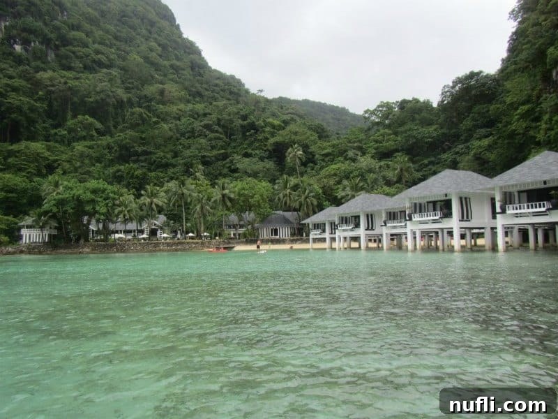Overwater bungalows on a lagoon with palm trees, depicting a serene private island retreat.