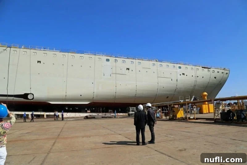 Workers at the Fincantieri shipyard overseeing the construction of the Carnival Horizon, with large ship sections visible.