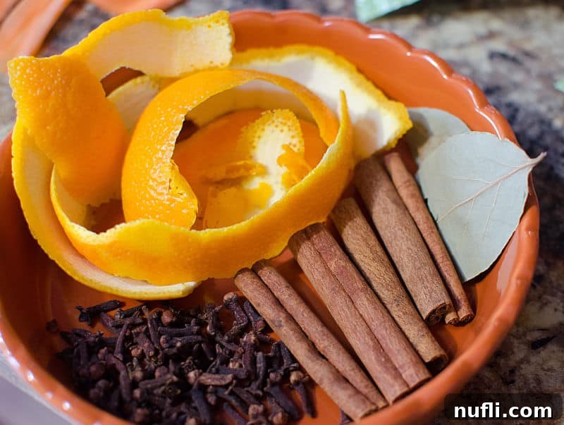 Cinnamon sticks, dried orange slices, and whole cloves arranged to make a festive potpourri, perfect for a crock pot recipe.