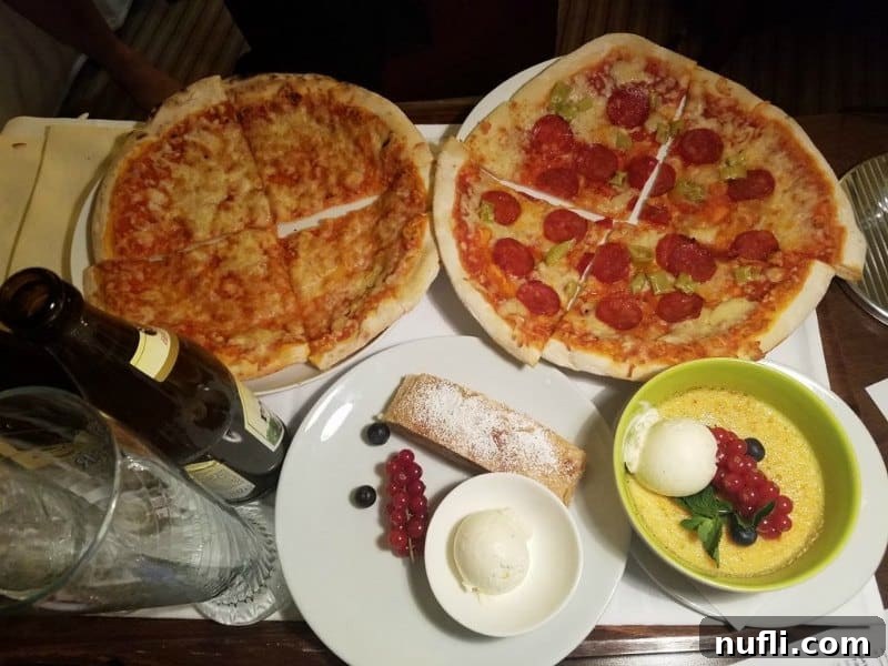 Two pizzas, a bowl of soup, and dessert served on a tray, indicating a cozy room service meal.