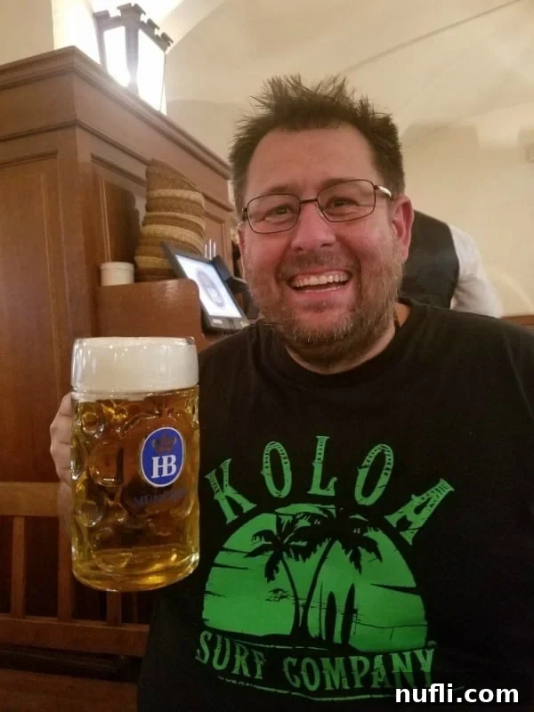 John holding a traditional Hofbräuhaus beer stein, a classic German souvenir.