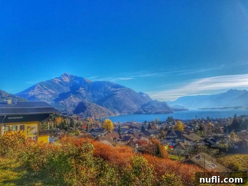A breathtaking lake surrounded by quaint houses and towering mountains under a clear sky.