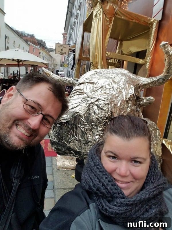 Tammilee and John posing with a giant gold bull statue, a playful moment captured during their travels.