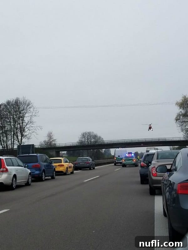A helicopter landing on a highway in front of cars stopped due to an accident, showcasing emergency response.