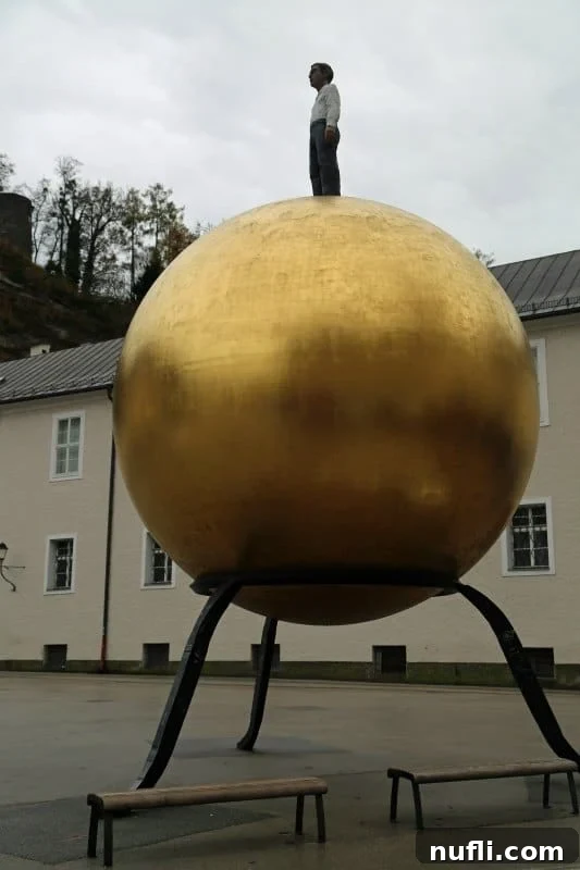 Sculpture of a man standing on a golden globe