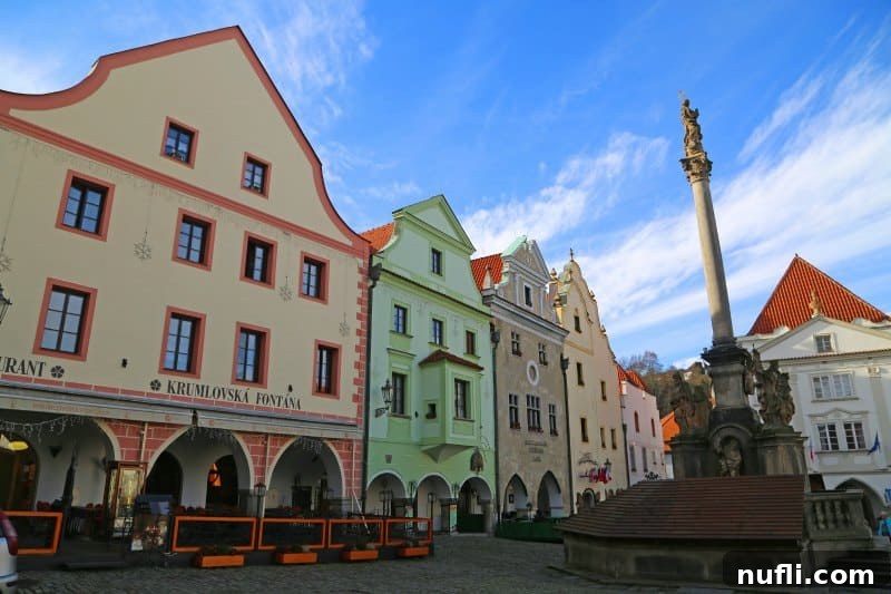 The bustling main square of Cesky Krumlov featuring pastel buildings and a central fountain