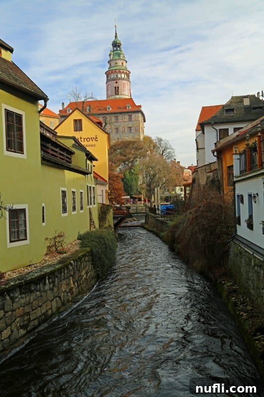 A picturesque view down the river, framed by buildings, towards the iconic Cesky Krumlov castle