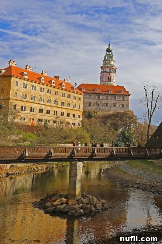 View across the Vltava River to a bridge, with people admiring Cesky Krumlov Castle in the background