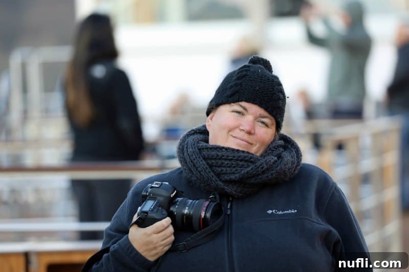 Cruising Austria's Wachau Valley with Viking 8 Traveler bundled up in a scarf and hat, holding a camera, ready to capture Wachau Valley scenery