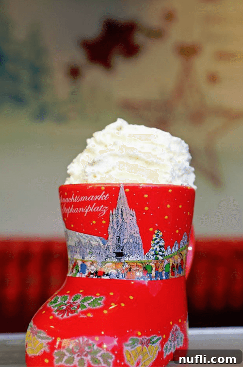 What Austria Taught Me I Needed 6 A festive red Christmas shoe mug filled with whipped cream, symbolizing a delightful treat from Austrian Christmas markets