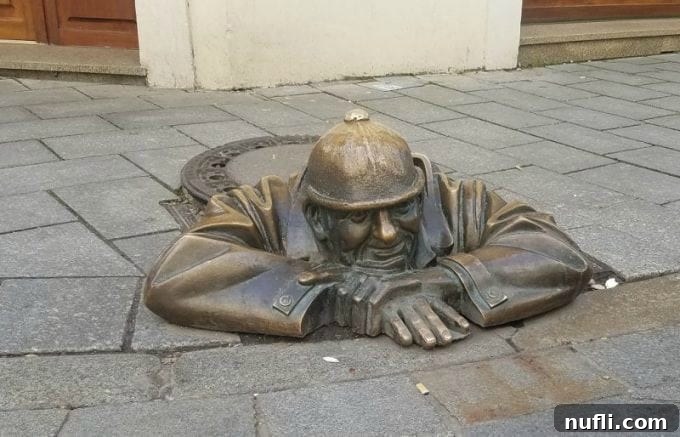 The famous Man at Work sculpture in Bratislava, peeking from a manhole