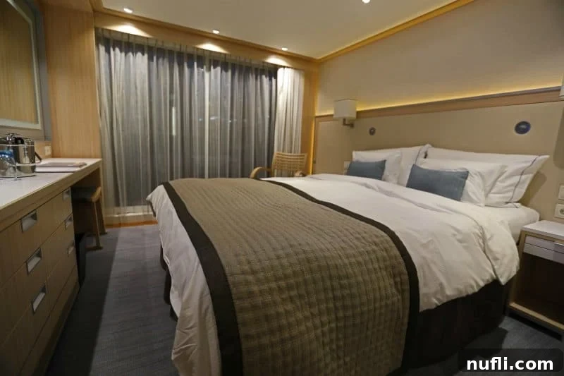 Discover the Viking Vili River Cruise Ship 4 Viking Vili stateroom with bed, chair, curtains closed and a desk/drawer area along the wall