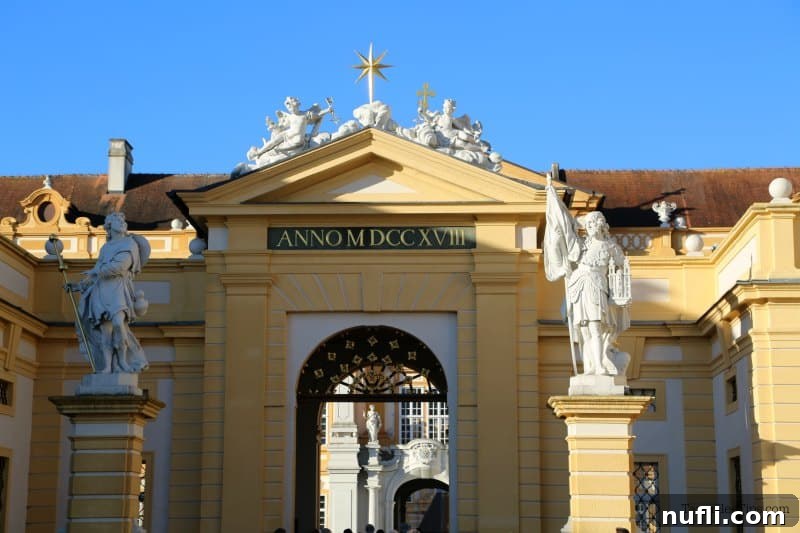 The impressive front entrance to Melk Abbey, flanked by two regal statues on ornate posts, warmly welcomes visitors to its historic grounds and the treasures within.