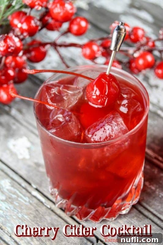 Festive Mulled Cherry Cider Cocktail 2 A vibrant red cherry cider cocktail garnished with a maraschino cherry, ready for holiday celebrations.