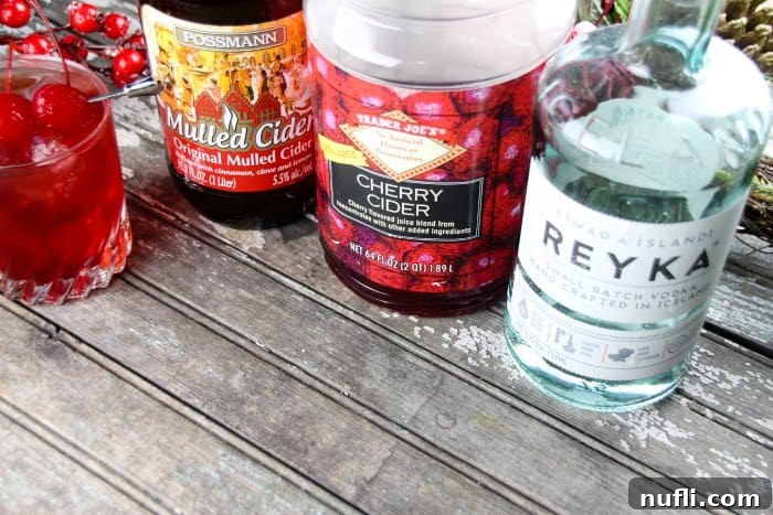 Festive Mulled Cherry Cider Cocktail 3 Bottles of mulled cider, cherry cider, and vodka, essential ingredients for the festive cocktail.