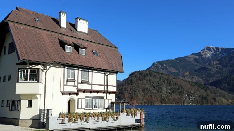 White building on a lake with mountains in the background, showcasing the beautiful St. Gilgen landscape