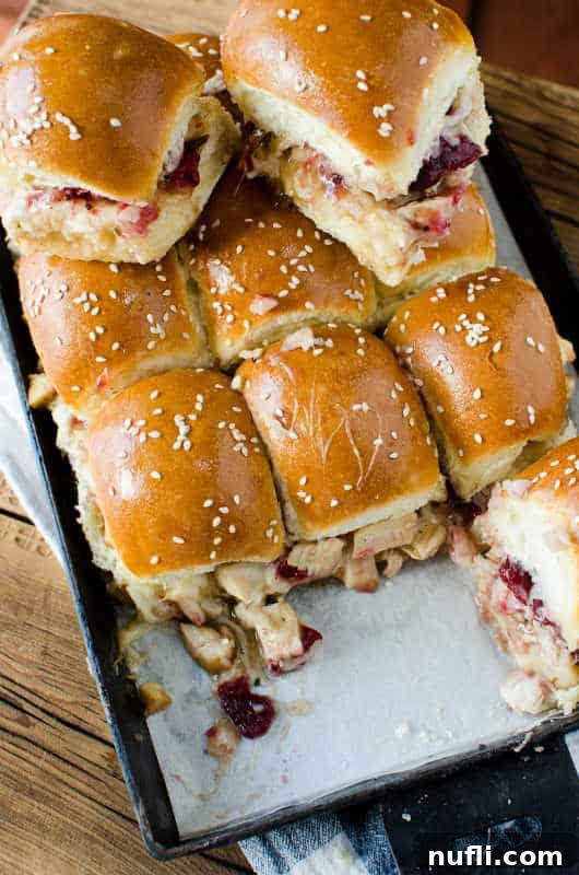 Freshly baked Cranberry and Leftover Turkey Sliders on a parchment-lined baking pan, ready to be cut.