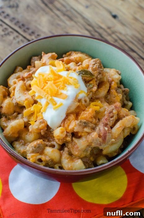 taco pasta garnished with sour cream and cheese in a bowl on an orange pot holder