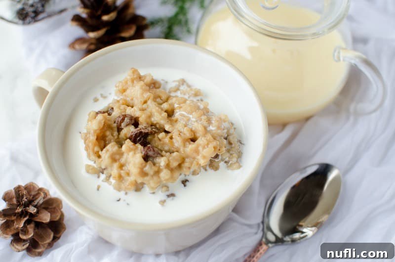 Slow Cooker Eggnog Oatmeal 5 A beautiful spread of Crock Pot Eggnog Oatmeal in a white bowl next to a spoon, pinecones, and a pitcher of eggnog, ready to serve