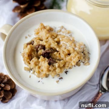 Slow Cooker Eggnog Oatmeal 6 Crock Pot Eggnog Oatmeal in a white bowl next to a spoon, a close-up of the delicious breakfast