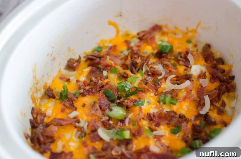 Decadent Slow Cooker Loaded Mashed Potatoes 6 bacon, melted cheese, onion on top of potatoes in a slow cooker