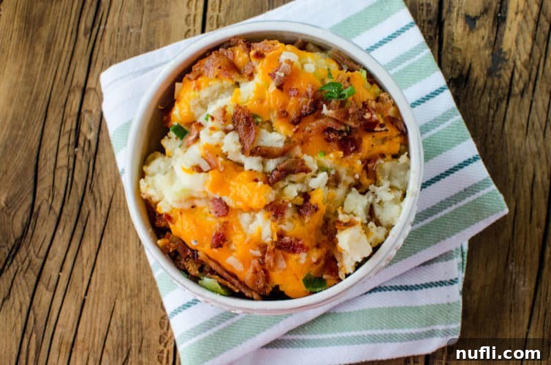 Decadent Slow Cooker Loaded Mashed Potatoes 7 bacon and cheese on loaded mashed potatoes in a white bowl on a cloth napkin