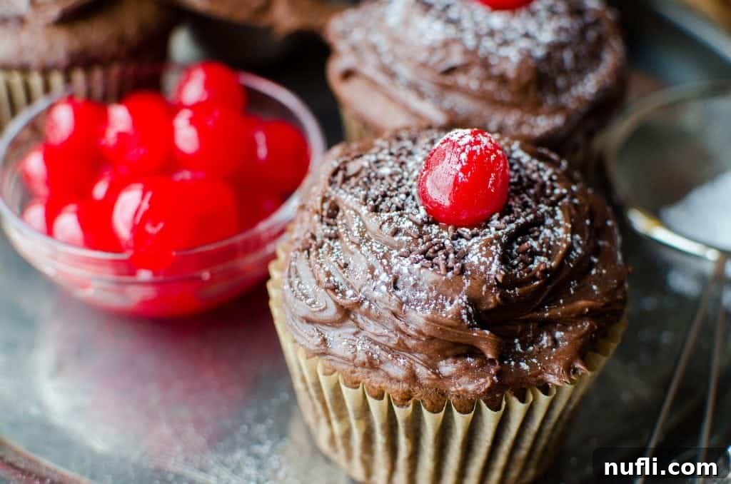 A batch of homemade Black Forest Cupcakes cooling on a wire rack, showcasing their perfectly baked tops before frosting.