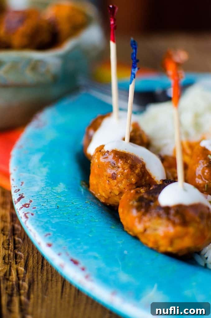 Crockpot buffalo chicken meatballs on a blue plate with toothpicks in them
