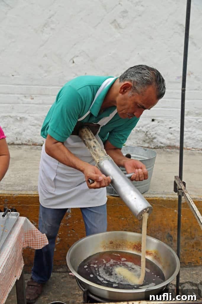 Gentleman pushing churro dough into a oil bath 