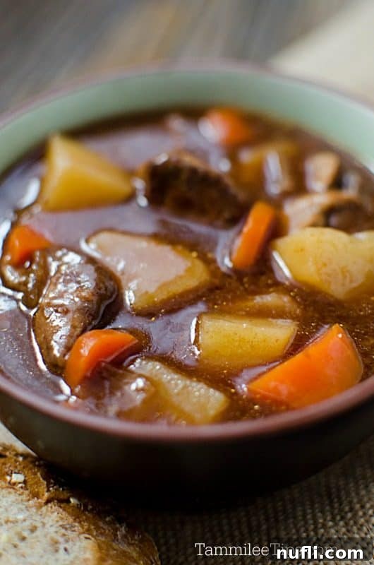 A warm bowl of Guinness Beef Stew with soda bread on the side, highlighting the rich brown color of the stew and the fluffy texture of the bread.