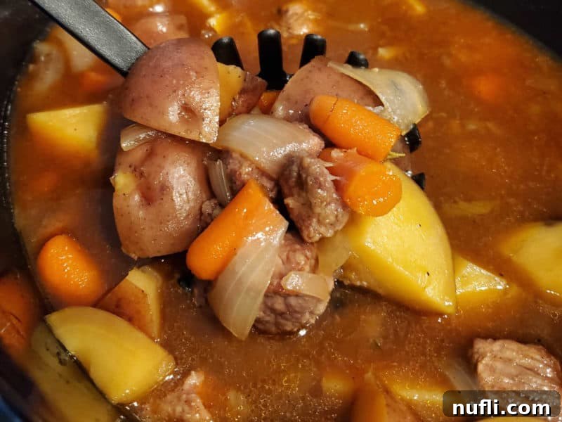 Guinness Beef Stew simmering in a slow cooker, showing the rich color of the broth and tender vegetables.