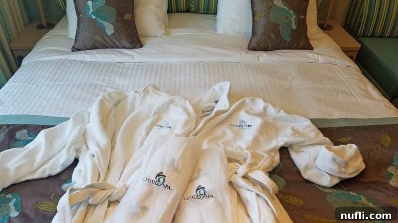 Two luxurious Cloud 9 robes and slippers arranged on the bed
