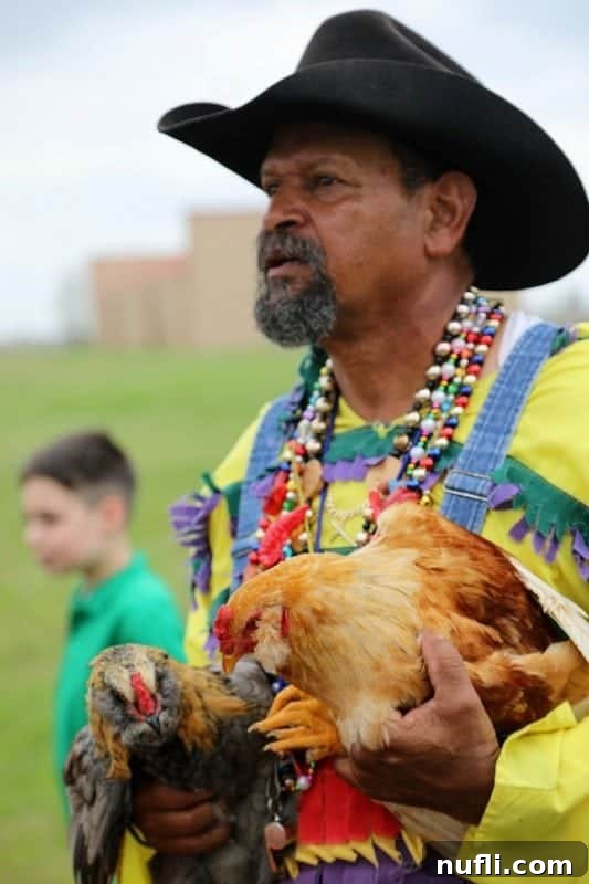 A man wearing a cowboy hat, smiling and holding two chickens, ready for the next round of the Iowa Chicken Run.
