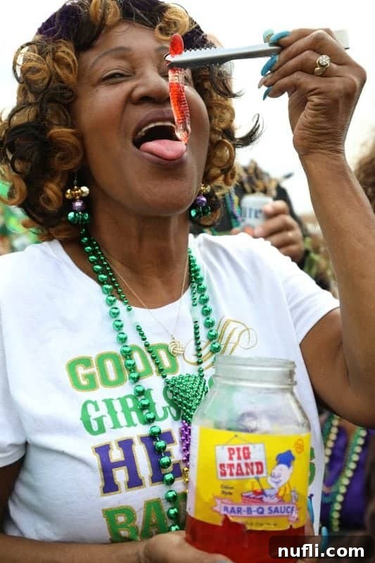 A woman using tongs to carefully pick a tequila-soaked gummy worm from a jar, ready to join the Mardi Gras festivities.