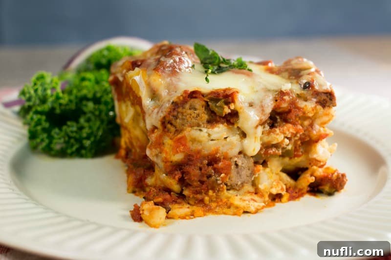 A close-up shot of a square piece of Crockpot Lasagna on a white plate, highlighting the tender pasta and rich filling.
