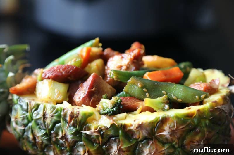 a pineapple filled with teriyaki chicken and vegetables on a wooden plate