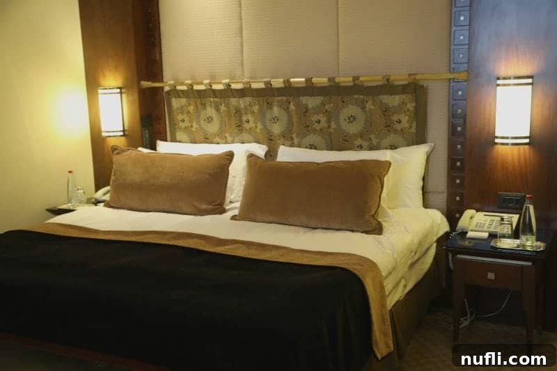 Bed with a unique headboard next to nightstand with phone and water bottles 