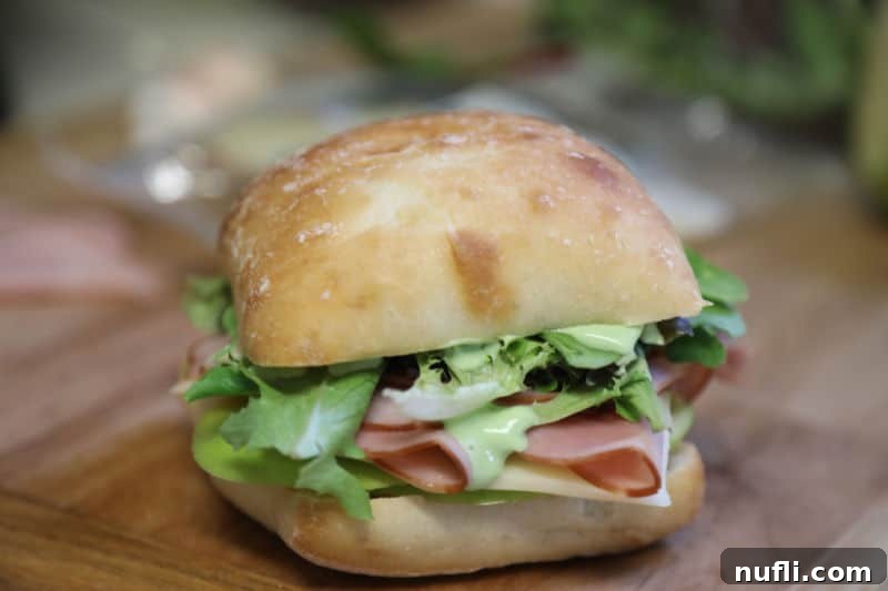 Garlic Aioli Ham and Swiss Ciabatta 4 A Ham and Swiss Ciabatta Sandwich with Garlic Aioli Recipe, beautifully arranged on a rustic wooden board, ready to be served.