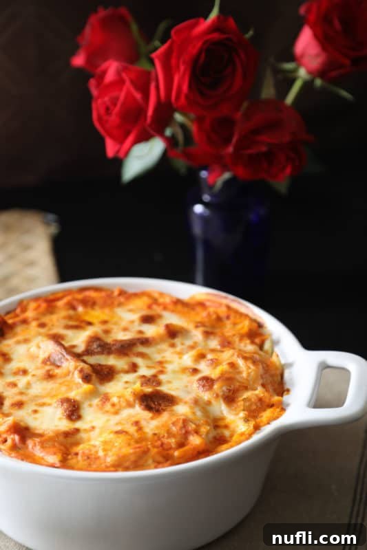 A baked cheese dish next to a vase of vibrant roses, creating a comforting and aesthetically pleasing dining scene.