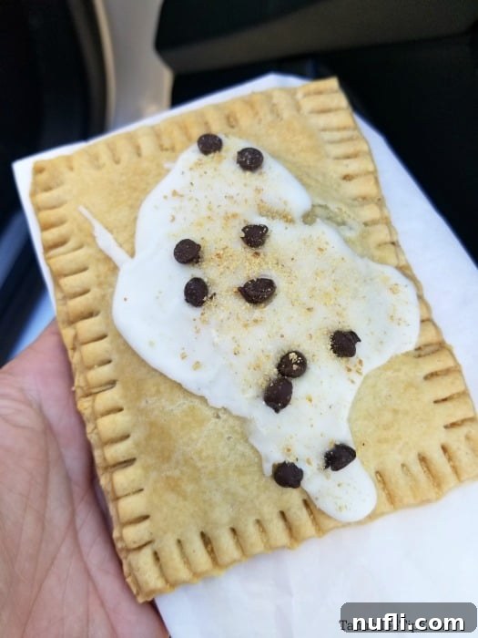 A delectable homemade Pop-Tart, speckled with chocolate chips, held delicately in a napkin, inviting a bite.