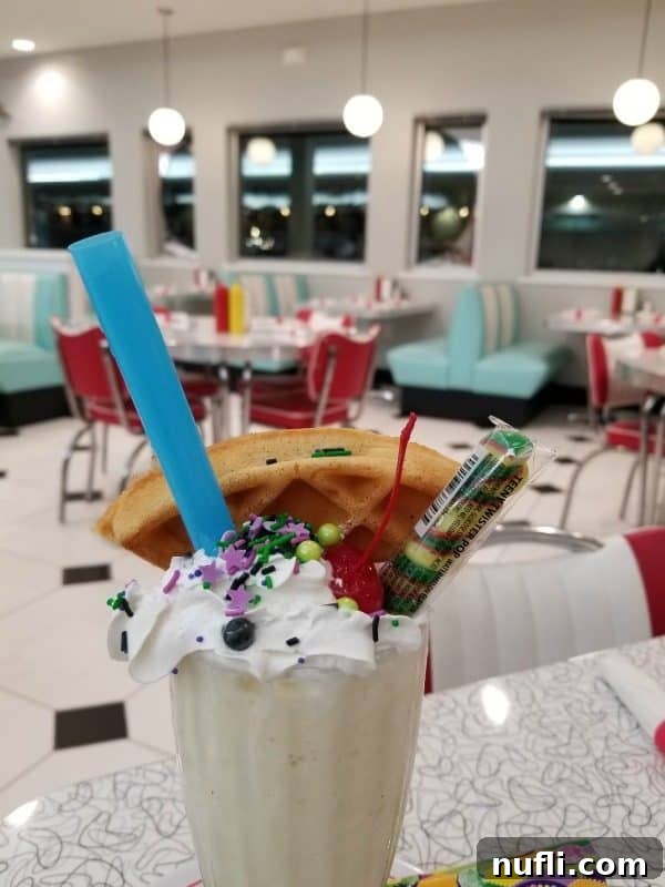 An elaborate Big Tickle Milkshake from Sunliner Diner, featuring a waffle, blue straw, and colorful sprinkles, embodying a playful and adventurous dessert.