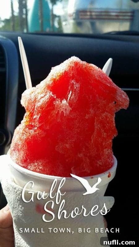 A refreshing shave ice in a white cup, subtly branded with a Gulf Shores logo, offering a cool relief on a hot day.