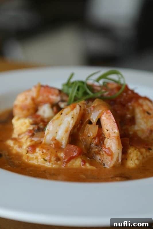 Best Things to Do in Orange Beach and Gulf Shores Alabama 14 A delectable plate of Shrimp and Grits, beautifully presented on a white plate, ready to be enjoyed at a Gulf Shores restaurant.
