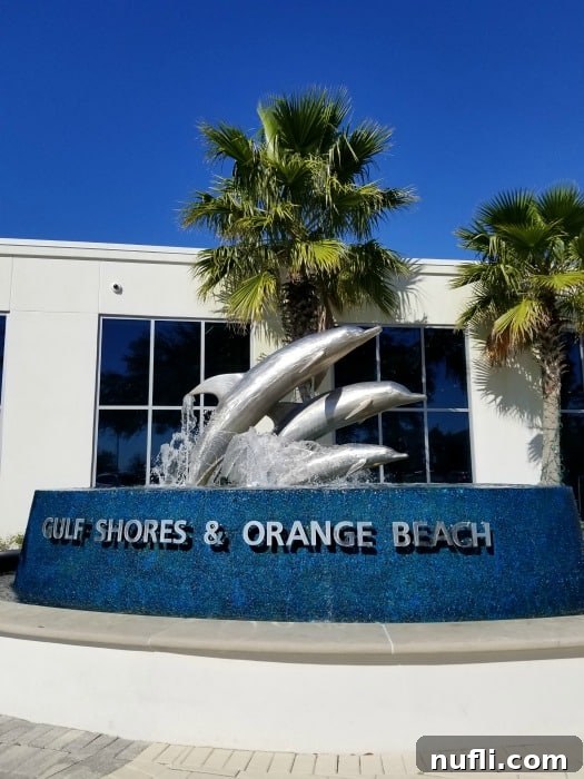 Best Things to Do in Orange Beach and Gulf Shores Alabama 4 A charming dolphin fountain in Gulf Shores, Orange Beach, framed by lush palm trees, welcoming visitors to this coastal paradise.
