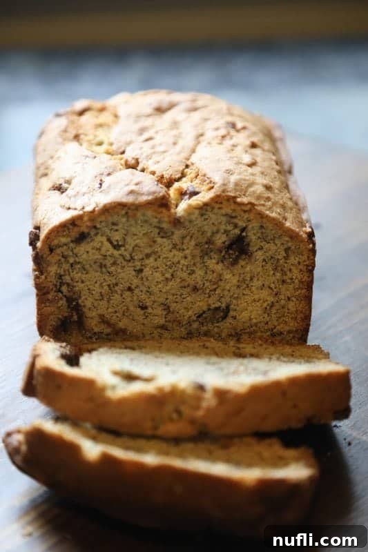 A perfectly sliced loaf of chocolate chip banana bread on a wooden cutting board, showing the soft texture and chocolate distribution.