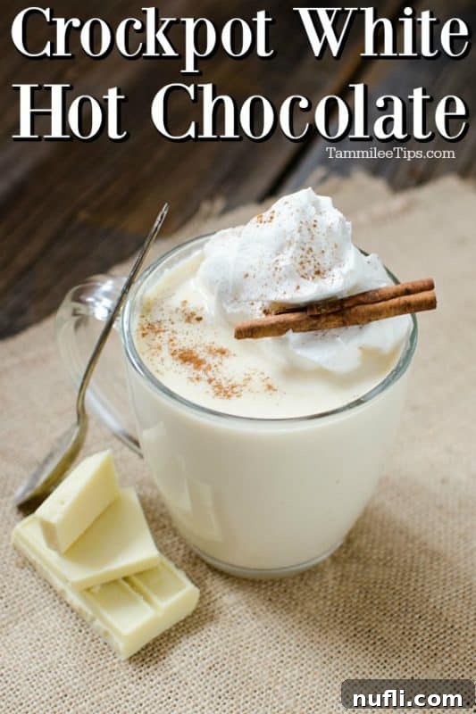 Crockpot White Hot Chocolate in a glass mug, garnished with whipped cream and a cinnamon stick. 